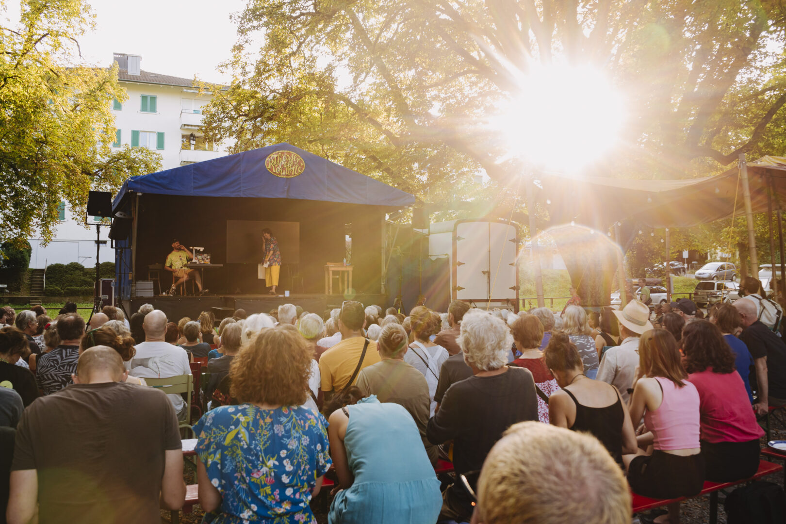 Festivalmoderation auf einer kleinen Bühne mit sitzendem Publikum